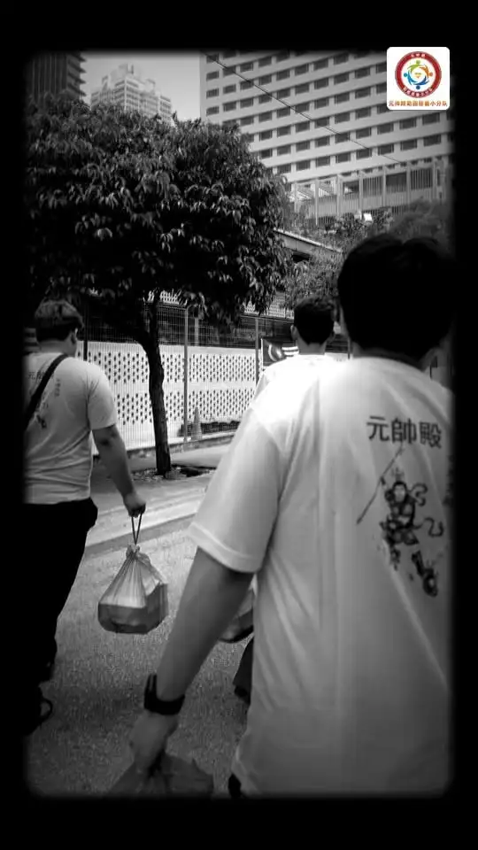 黑白照片：义工提着饭盒，沿着城市街道一路走一路派